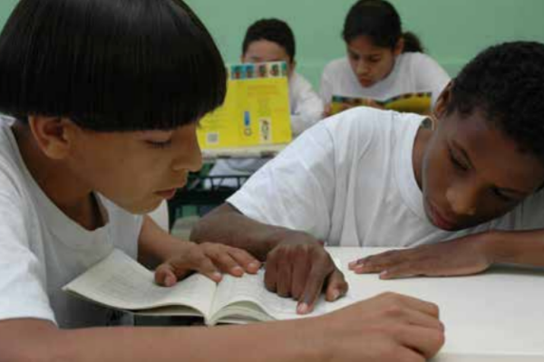 dois alunos se ajudam nas tarefas na sala de aula
