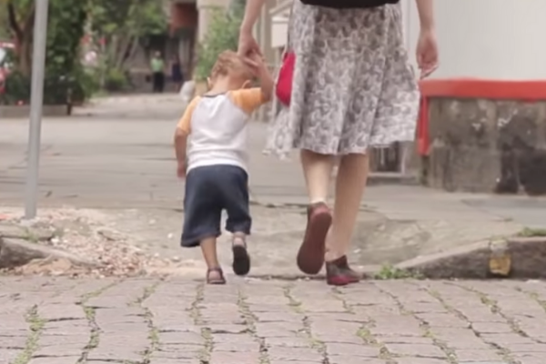 crianca de 1 ano e meio andando de mão dadas com a mãe na rua